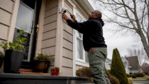Man installing home security camera on porch