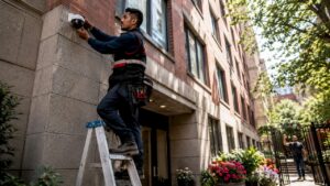 Technician installing CCTV at apartment entrance