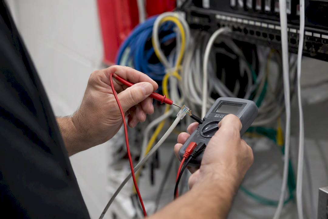Technician measuring cable voltage with multimeter