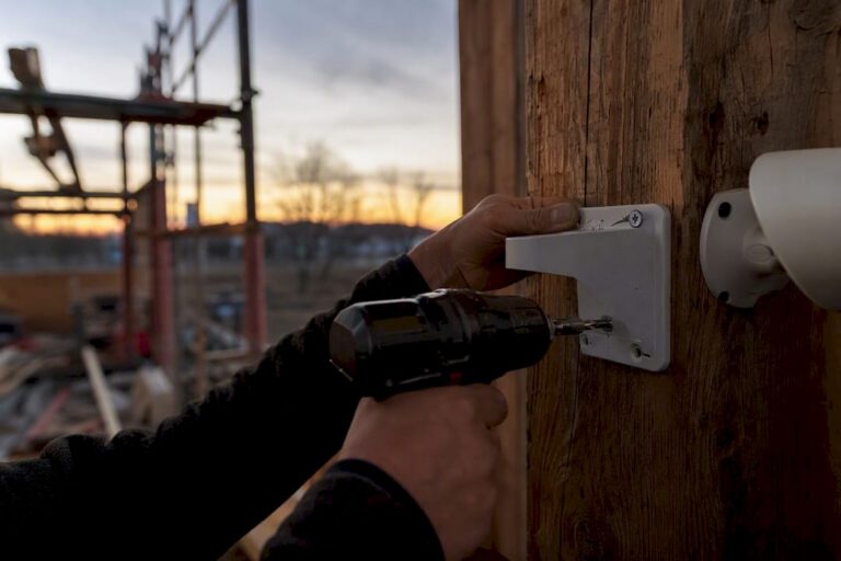 Hands installing security camera bracket on steel beam