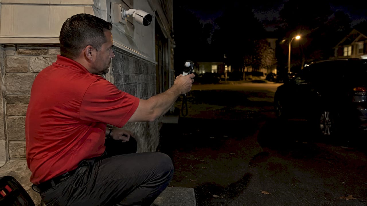 Technician measuring light near security camera